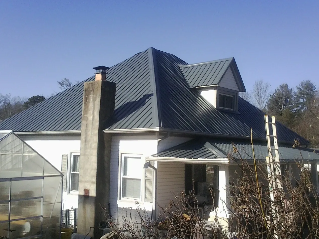 Dark blue standing seam metal roof on a white farmhouse with dormer — Slate & Tile Roof Repair by Roofing Brothers in Needham