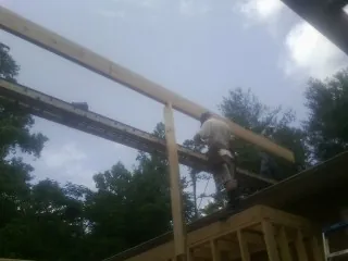 Carpenter setting a ridge beam over a new addition frame — Ice Dam Removal by Roofing Brothers in Needham