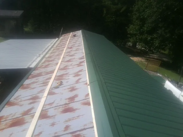 Old rusted panels beside newly installed green metal roofing — Wind Damage Roof Repair by Roofing Brothers in Needham