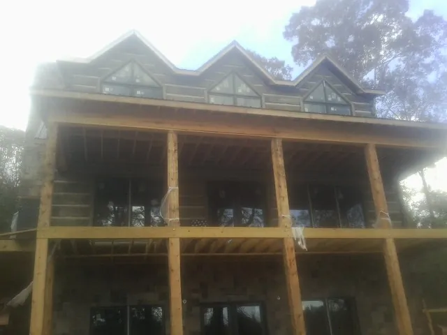 Dormers and porch framing on a large log home under construction — Roof Coating work by our crew in Needham