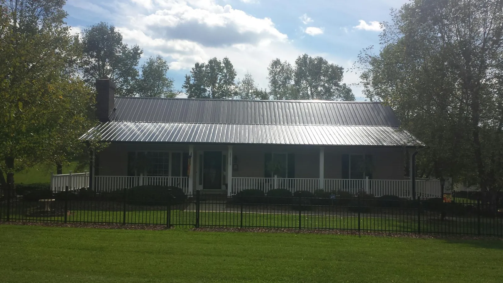 Gray metal roof on a brick ranch with a full width front porch — Gutter Guard Installation work by our crew in Needham