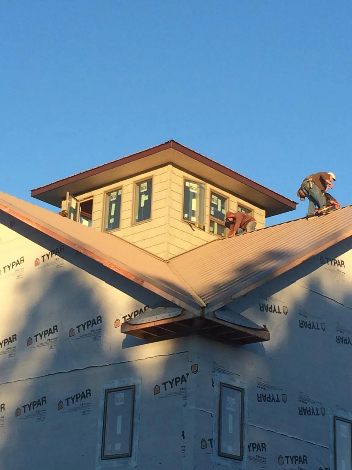 Roofers working around a rooftop cupola on a new metal roof at sunset — Roof Waterproofing in Needham by Roofing Brothers